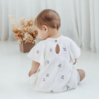 Baby wearing a white onesie with floral patterns on a white background