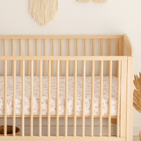 Nursery room with a wooden crib, macrame wall hanging, and decorative arch.