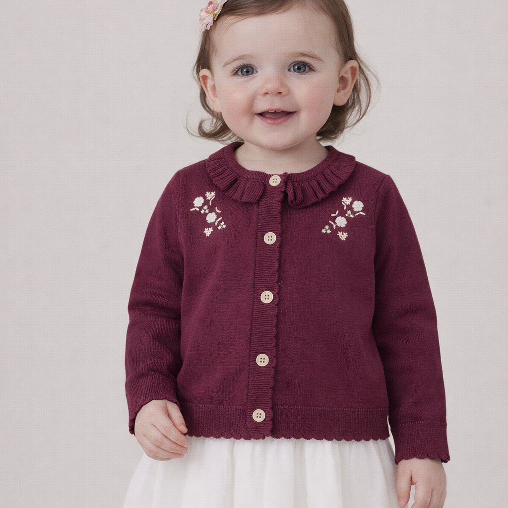Child wearing a maroon cardigan with floral embroidery on a plain background