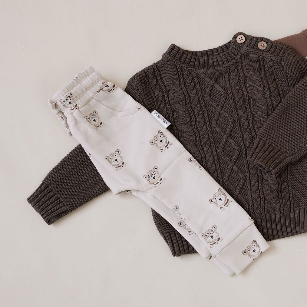 Children's clothing set including a sweater, pants, shirt, and hat on a light background