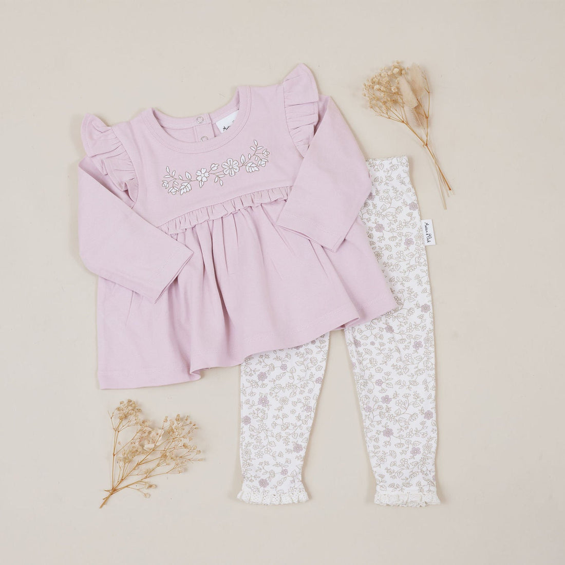 Pink baby top and white patterned leggings on a beige background