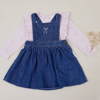 Children's denim pinafore dress with white shirt on a light background