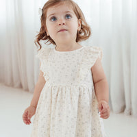 Young girl wearing a white lace dress against a white curtain background